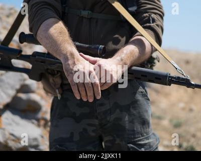 Vista ravvicinata delle mani di un cecchino. Il concetto di conflitti militari moderni e di operazioni speciali. Foto Stock