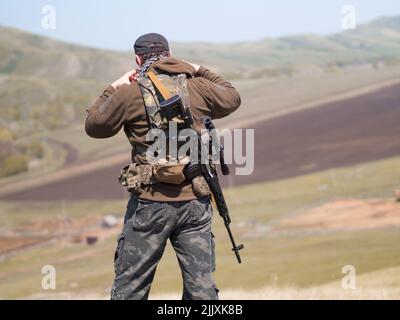 Uomo militare con fucile da cecchino, all'aperto, vista dal retro. Conflitto militare mediorientale. Foto Stock