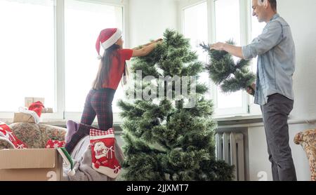 Giovane padre con daugter che adornano l'albero di Natale insieme Foto Stock