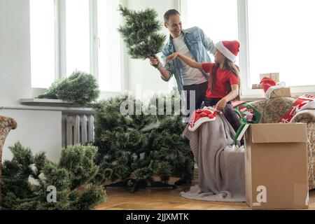 Giovane padre con daugter che adornano l'albero di Natale insieme Foto Stock