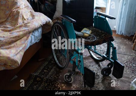 sedia a rotelle vuota in una vecchia casa molto povera Foto Stock