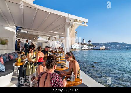 Tempo di caffè nella famosa 'piccola Venezia' presso l'isola Chora di Mykonos con i mulini a vento sullo sfondo. CICLADI, Mar Egeo, Grecia. Foto Stock