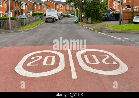 Llantrisant, Galles - Luglio 2022: Segnaletica stradale che mostra 20 mph velocità limitata dipinta sulla strada all'ingresso di una proprietà immobiliare. Foto Stock