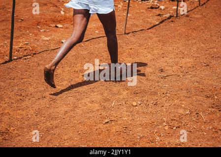 Corsa a piedi nudi donna che corre su terra rossa africana in Kenya. Correre in Kenya senza scarpe. Vita semplice in Africa Foto stock Alamy