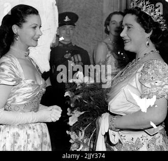 Queen, diamante tiara e Ruby e diamanti orecchini scintillanti, sopra il suo abito crinolina satin, parlando con l'attrice britannica Vivien Leigh dopo lo spettacolo. Nelle scene che ricordano l'anno scorso, quando la famiglia reale era quasi assalita da folle paurose, una sezione dell'enorme trono si è rotta attraverso il forte cordone di polizia del 1.000 a Leicester Square London, E portò l'auto della famiglia reale a fermarsi quando arrivarono per il Royal Command Film Show al Teatro Odeon. La polizia ha rapidamente spiovato un percorso per l'auto e il re e la regina con la principessa Margaret, guidato verso l'Odeon. Novembre 25, 1947. Foto Stock