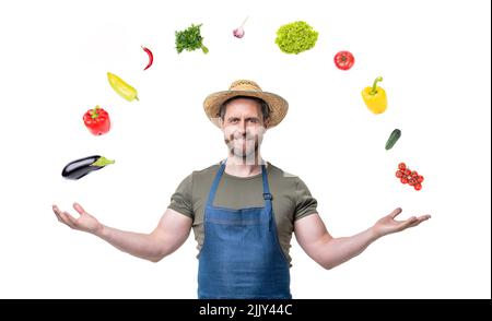 uomo felice in cappello di paglia e grembiule con verdure colorate isolate su sfondo bianco Foto Stock