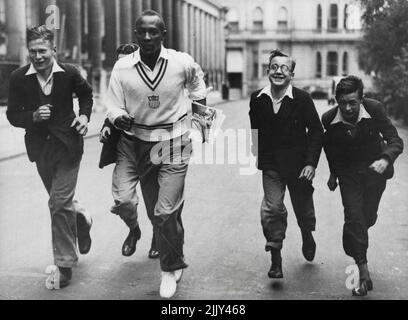 Gli atleti olimpici americani di Londra dove si competeranno in un concorso atletico contro una squadra inglese allo stadio di White City, il 15th agosto. Jesse Owens, il famoso corridore americano, mostra ad alcuni ragazzi messaggeri "come farlo". Agosto 14, 1936. (Foto di Sport & General Press Agency, Limited). Foto Stock