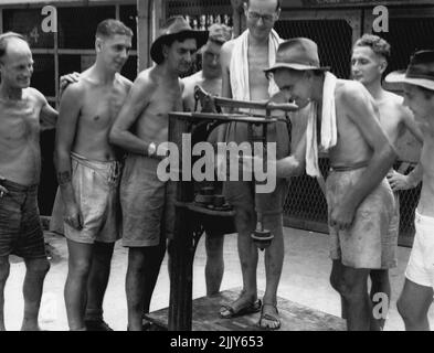 Membri della Divisione 8, ex prigionieri di guerra dei giapponesi, controllando i loro guadagni di peso su una serie di scale nel cortile della prigione. Settembre 19, 1945. (Foto di Australian War Memorial Canberra). Foto Stock