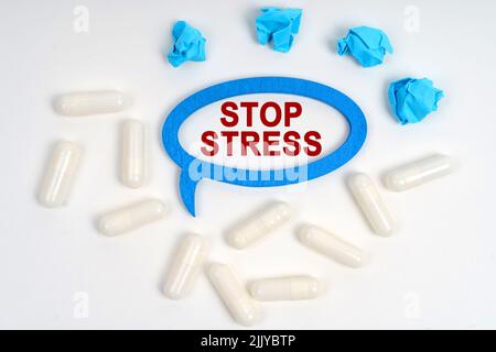 Concetto di medicina. Su un bianco di sfondo pillole, grattato blu pezzi di carta e una cornice-pensieri con l'iscrizione - STOP STRESS Foto Stock