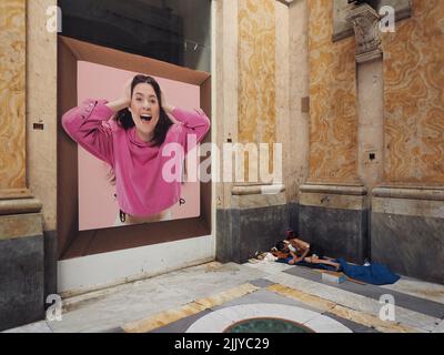 Uomo senza tetto che dorme in un angolo del centro commerciale Galleria Umberto 1 nel centro di Napoli, con grande poster di moda di donna graziosa, Napoli, Camp Foto Stock