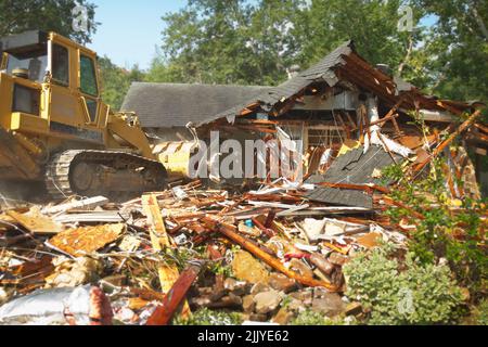 Esterno di casa residenziale in fase di demolizione con bulldozer preparazione per la nuova costruzione Foto Stock