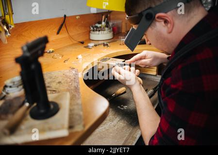 un gioielliere lavora con un pezzo di gioielleria, le mani di un gioielliere Foto Stock