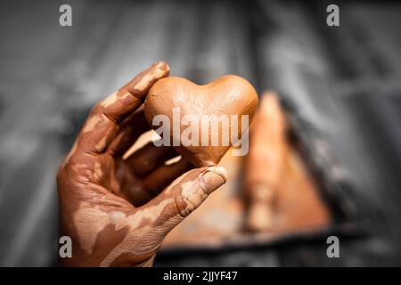 Cuore fatto di argilla del vasaio nelle mani di un vasaio maestro. Concetto di amore Foto Stock