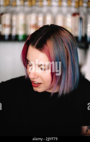 Giovane barista femminile con capelli multicolore in caffetteria Foto Stock