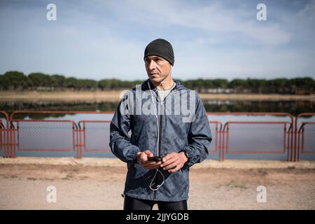 Uomo runner con telefono sul lago Foto Stock