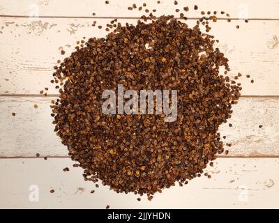 Un mucchio di bucce di grano saraceno organico usato come riempimento per cuscino di grano saraceno su un fondo di assi di legno Foto Stock