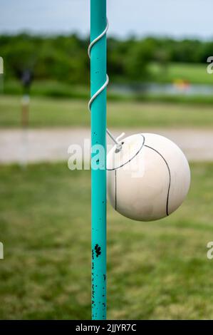 Tetherball seduto inattivo accanto al palo in un cortile. Foto Stock