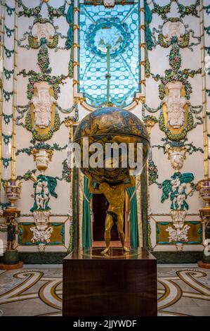 Un colpo verticale di un'antica figura dell'Atlante Farnese che tiene il mondo all'interno del Palazzo reale di Madrid Foto Stock