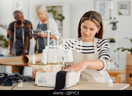 Moda, design e lavoro creativo in un laboratorio tessile. Giovane lavoratrice femminile che stitching abiti alla moda e alla moda in una startup. Occupato su misura Foto Stock