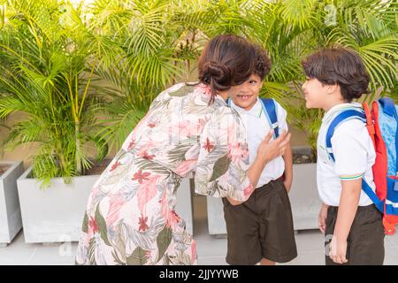 Madre latina con i suoi figli che dice a Arrivederci di andare a scuola Foto Stock