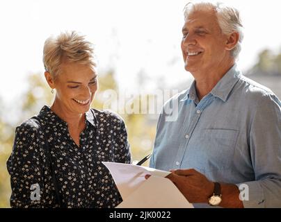 Ceneri eccitato per iniziare un nuovo capitolo. Un realtor maschio anziano che passa attraverso il lavoro di ufficio con un cliente. Foto Stock