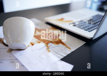 Questo giorno non poteva peggiorare: Durante il giorno c'era un caffè versato su documenti e un computer portatile in una cucina vuota. Foto Stock