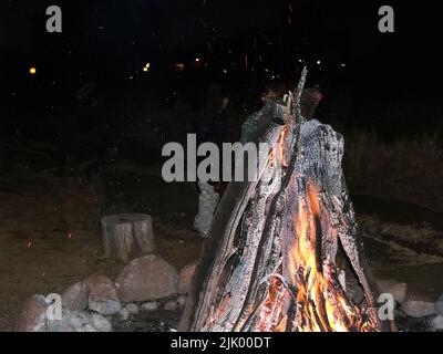 Legno ardente con fiamme calde, schema incrinato di legno di carred e scintille che volano intorno in notte Foto Stock