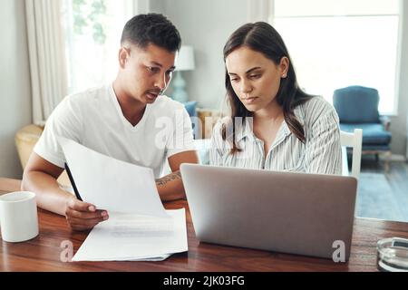 Controllare le cifre. Una giovane coppia che usa un computer portatile al proprio budget domestico nel soggiorno di casa. Foto Stock