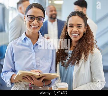 Le Signore principali. Ritratto di due donne d'affari in un ufficio con i loro colleghi in background. Foto Stock