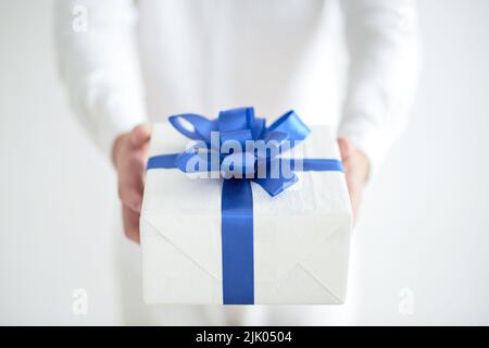 Primo piano immagine del presente con nastro blu nelle mani del giovane uomo Foto Stock