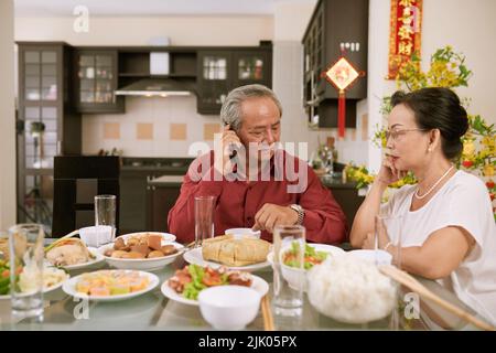 Coppia anziana in attesa dei loro figli e nipoti per la cena di Capodanno cinese. Scorre desiderio di fortuna e ricchezza in background Foto Stock