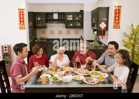 Grande famiglia asiatica godendo la festa cinese di Capodanno in casa. Scorre desiderio di fortuna e ricchezza in background Foto Stock