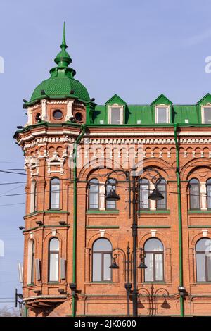 Parte della facciata di un edificio rosso con molte finestre. Facciata della casa di vecchio edificio storico. Vecchio edificio storico con pareti rosse Foto Stock