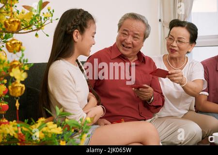 Coppia vietnamita senior che danno buste di soldi fortunati alla loro nipote Foto Stock