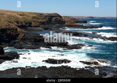 Guardando verso est lungo la costa sud di Phillip Island a Victoria, Australia, la vista è rocce e onde infrangenti, tipico di Bass Strait. Foto Stock