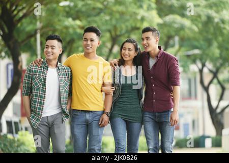 Gruppo di allegri amici vietnamiti che si godono a piedi all'aperto Foto Stock