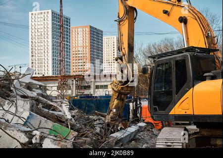 L'escavatore con forbici idrauliche taglia travi in calcestruzzo Foto Stock