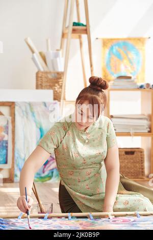 Donna piuttosto giovane concentrata sulla pittura Foto Stock