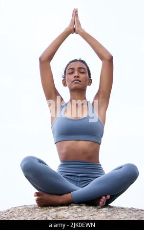 Esercizio per la mente. Scatto a tutta lunghezza di una giovane donna attraente meditando mentre si pratica yoga sulla spiaggia. Foto Stock