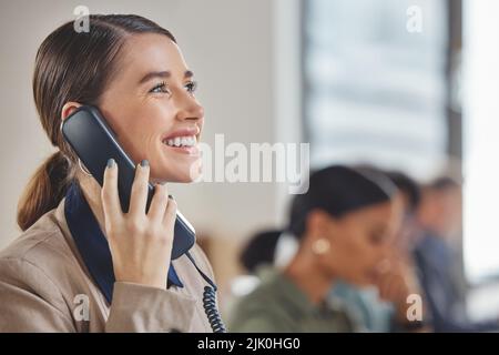 Una giovane donna d'affari che parla al telefono mentre lavora in un call center. Foto Stock