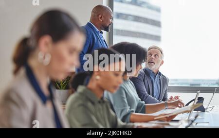 Avete bisogno di aiuto per chiudere la vendita. Un uomo d'affari maturo che assiste un collega in un call center? Foto Stock