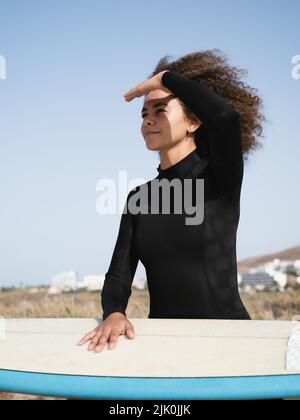 Ritratto ragazza surfer multirazziale guardando le onde Foto Stock