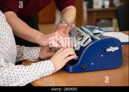 Un uomo insegna a una donna cieca a scrivere su una macchina braille. Foto Stock