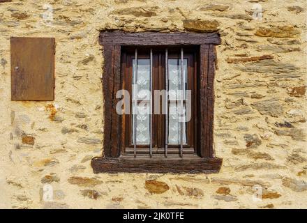 Finestra di legno nella vecchia facciata di casa in pietra in colori luminosi. Madrid. Foto Stock