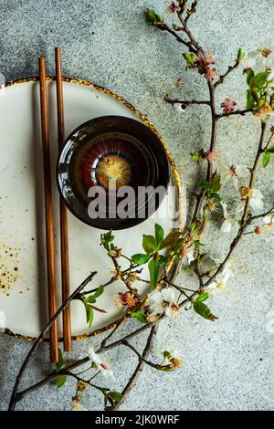 Tavolo primaverile con bacchette decorate con rami di ciliegio fiorenti Foto Stock