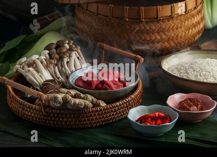 Ingredienti per la cucina asiatica in una vaporiera di bambù (riso, funghi asiatici e manzo) Foto Stock