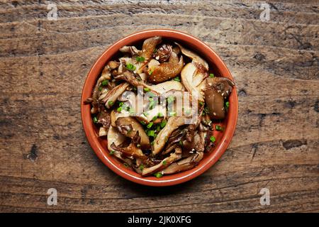 Funghi e erba cipollina in un piatto di tapas in terracotta Foto Stock