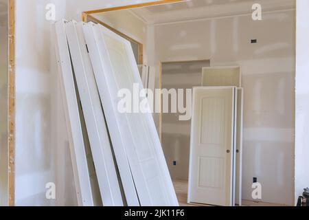 L'installazione di porte impilatrici bianche all'interno di una nuova casa è in fase di preparazione Foto Stock