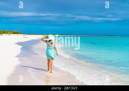 Bella donna che cammina su idilliaca spiaggia bagnata dal Mar dei Caraibi, Barbuda, Antigua e Barbuda, Indie Occidentali, Caraibi, America Centrale Foto Stock