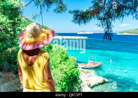 Donna che contempla il mare cristallino che si erge sotto gli alberi in ombra sulla collina, Porto Atheras, Cefalonia, Isole IONIE, Isole Greche, Grecia Foto Stock